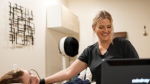 Natalie smiling while scanning a patient's neck
