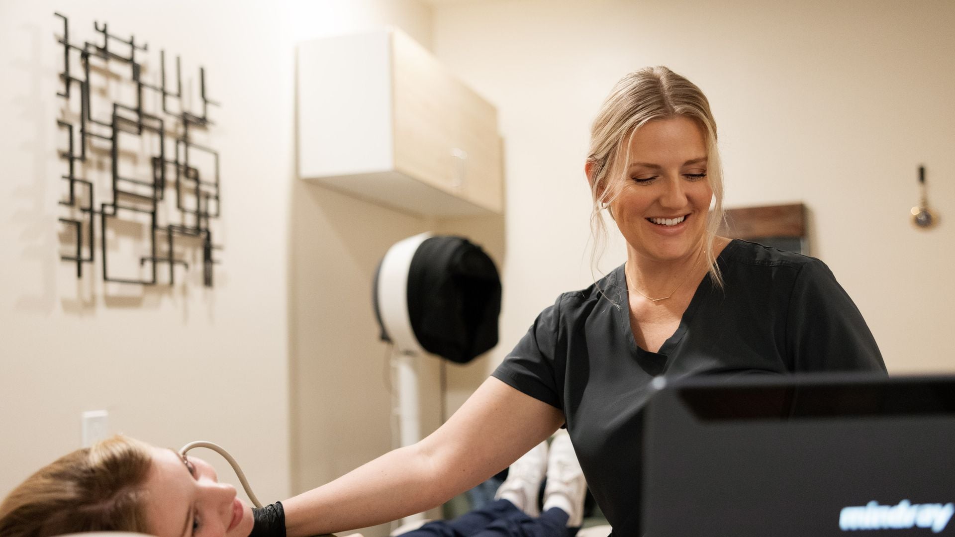 Natalie smiling while scanning a patient's neck