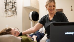 Natalie smiling while scanning a patient's neck